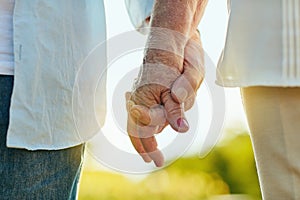 Hold each others hand and feel safe in loves embrace. a senior couple holding hands in a park.