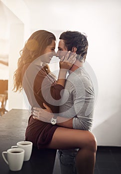 Hold me close and kiss me. an affectionate young couple hugging in the kitchen at home.