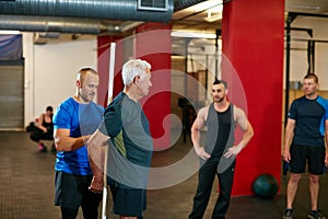 Hold onto this...a senior man doing pvc pipe exercises with the assistance of his trainer.