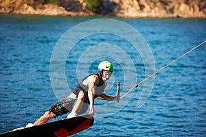 Hold on tight and never let go. Wakeboarder grabbing the front of his board while performing a front boardslide trick -