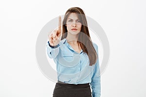 Hold on, wait a sec. Bossy displeased attractive entrepreneur in blue official blouse, frowning and pulling index finger