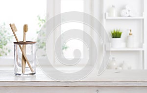 Holder with bamboo toothbrushes on wooden table against defocused background