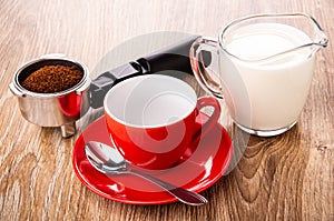 Holder from coffee maker with coffee, jug of milk, cup, spoon on saucer on table