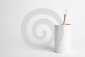 Holder with eco bamboo toothbrush on white background.