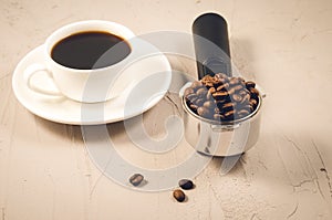 holder filled with beans and coffee cup/holder filled with beans and coffee cup on a stone background, selective focus