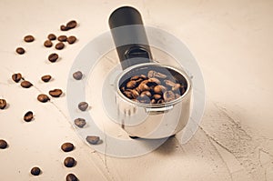 holder filled with coffee beans/Filter holder filled with coffee beans on a concrete background. Selective focus