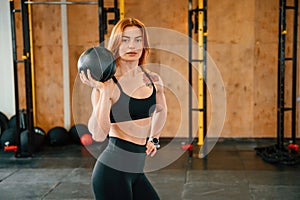 Holding ball. Beautiful strong woman is in the gym