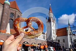 holding bayern style pretzel on the victuals market with altes rathaus background in munich