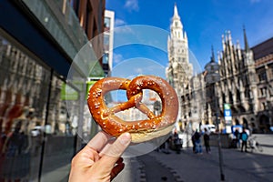 holding bayern style pretzel on the victuals market with Neues Muncher Rathaus background in munich