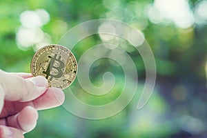 Bitcoin in hand with green blur background, bitcoin concept, copy space