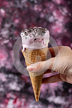 Holding a blueberry icecream in waffle cone in the hand