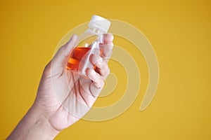 holding bottle with liquid medicine on yellow