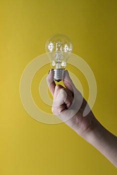 Holding Bulb idea on yellow background