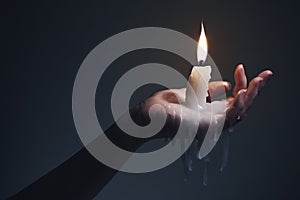 Holding a candle on a dark background.