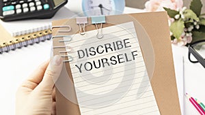 holding a card with DESCRIBE YOURSELF message, business concept image with soft focus background