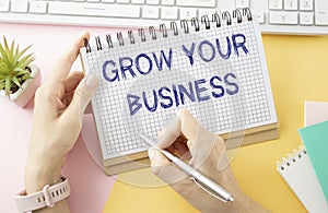 Holding a card with text GROW YOUR BUSINESS