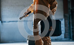 Holding case and flashlight. Man dressed in chemical protection suit in the ruins of the post apocalyptic building