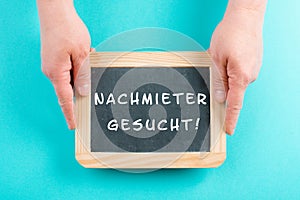 Holding a chalkboard in the hands, looking for a new tenant is standing in german language on the sign, moving to a new home