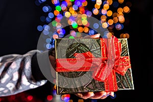 Holding Christmas gift isolated on background with blurred lights. December season, Christmas composition