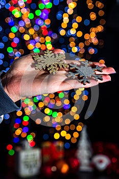Holding Christmas snowflake decoration  on background with blurred lights. December season, Christmas composition