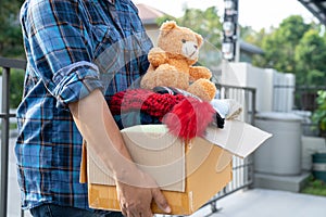 Holding clothing donation box with used clothes and doll at home to support help for poor people in the world