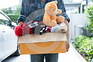 Holding clothing donation box with used clothes and doll at home to support help for poor people in the world