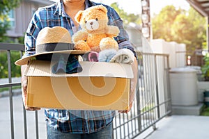 Holding clothing donation box with used clothes and doll at home to support help for poor people in the world