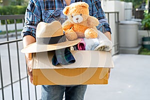 Holding clothing donation box with used clothes and doll at home to support help for poor people in the world