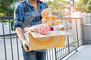 Holding clothing donation box with used clothes and doll at home to support help for poor people in the world