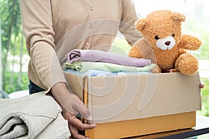 Holding clothing donation box with used clothes and doll at home to support help for poor people in the world