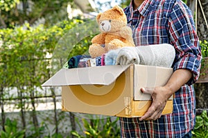 Holding clothing donation box with used clothes and doll at home to support help for poor people in the world