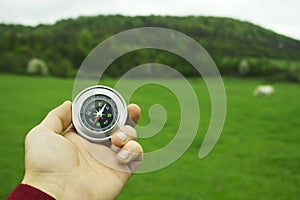 Holding a compass on the background of a green field