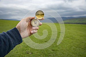 Holding a compass on the background of a green field
