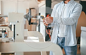 Holding controller of printing machine. Polygraph worker in white clothes is indoors