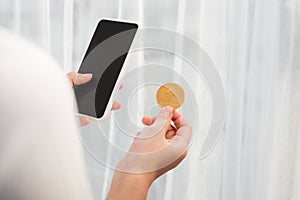 Holding crypto coin and mobile phone on white background