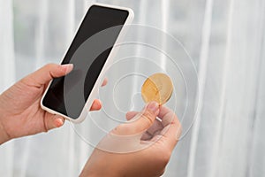 Holding crypto coin and mobile phone on white background