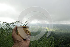 Holding a cup of coffee on the hill - mountain range