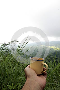 Holding a cup of coffee on tophill - mountain range