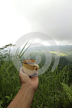Holding a cup of coffee on tophill - mountain range