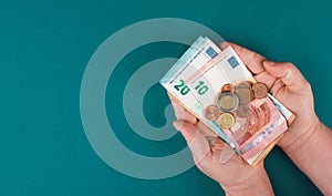 Holding Euro banknotes and coins in the hands, counting money, saving income