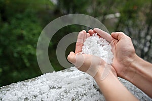 Holding freezing granulated hail ice crystals, grains in hands after strong hailstorm in autumn, fall.