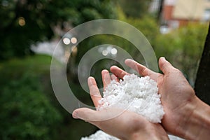 Holding freezing granulated hail ice crystals, grains in hands after strong hailstorm in autumn, fall.