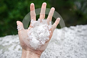 Holding freezing granulated hail ice crystals, grains in hands after strong hailstorm in autumn, fall.