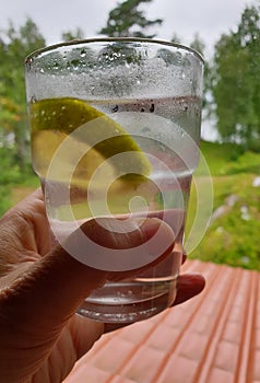 Holding a frosty gin and tonic glass with nature background