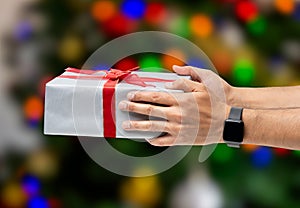 holding gift box over Christmas tree