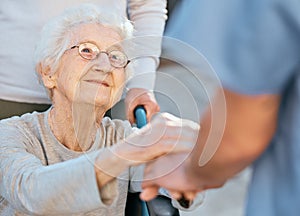 Holding hands, caregiver and senior woman in wheelchair for support outdoor in retirement home. Love, trust and