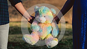 Holding hands with a colorful teddy bear