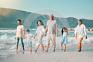 Holding hands, family is walking on beach and ocean, generations and bonding in nature with waves. Grandparents, parents