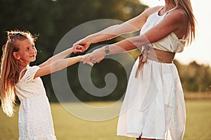 Holding by the hands. Mother and daughter enjoying weekend together by walking outdoors in the field. Beautiful nature