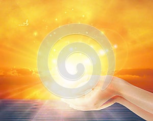 Hands with spark of hope, holding the sun, the light of faith, spiritual freedom, yellow sunetbackground